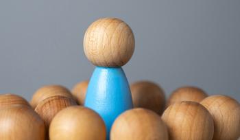 Wooden people are placed in a circle around one wooden person standing above the circle